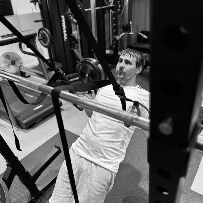 Man rowing on a Concept2 machine, working out in a gym.