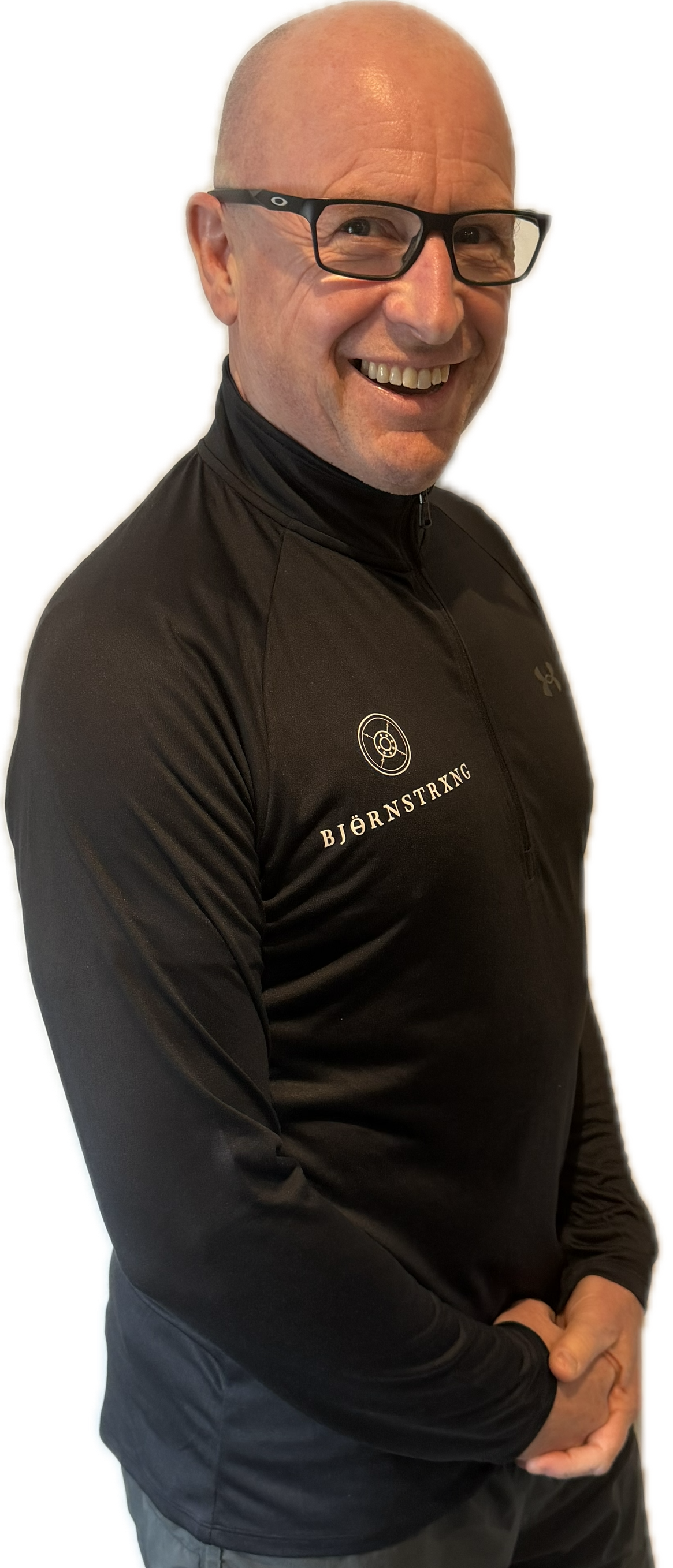 Man with a beard wearing a white polo shirt and gray pants, standing with hands behind back.
