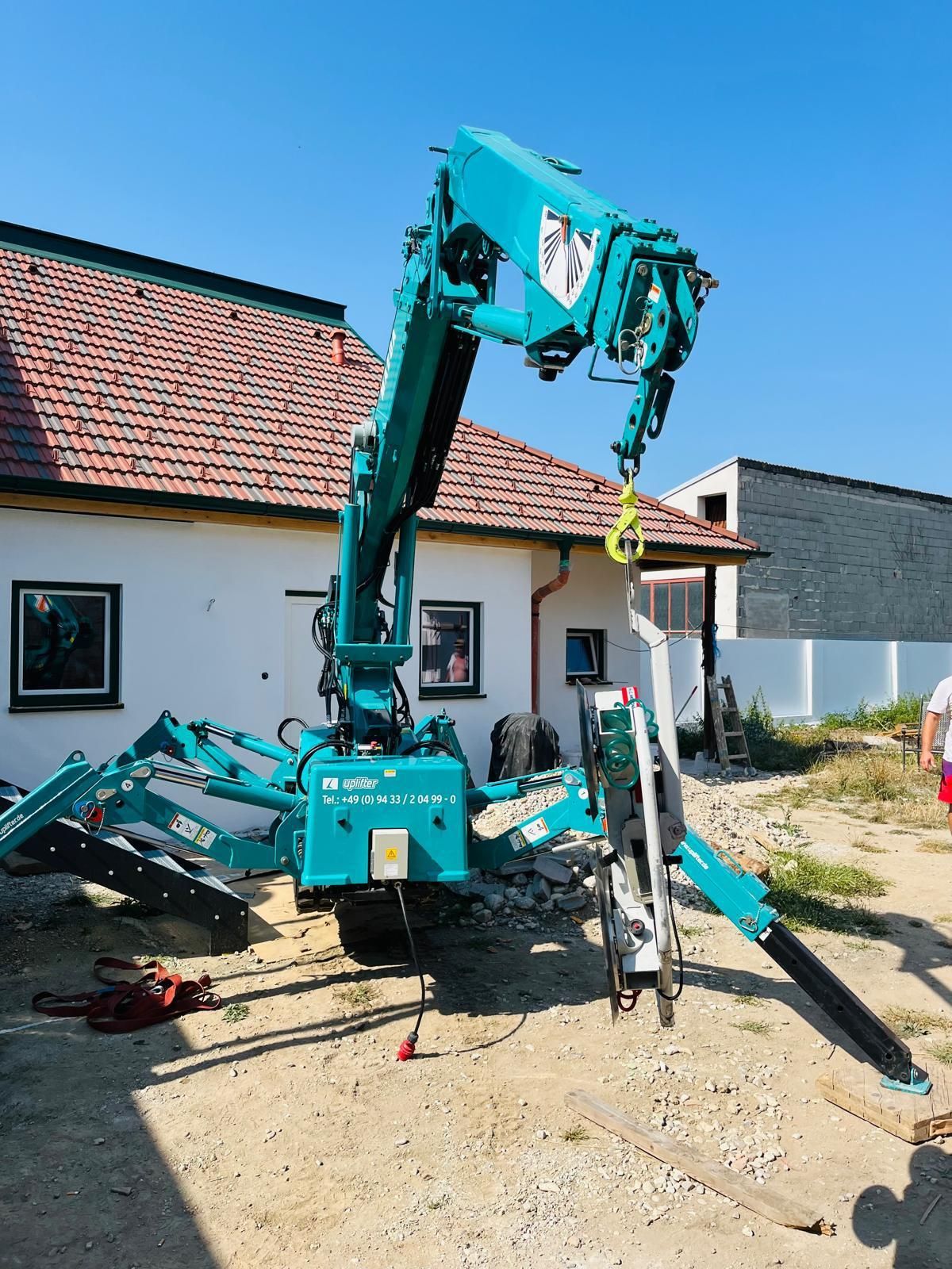 Ein blauer Kran steht vor einem Haus