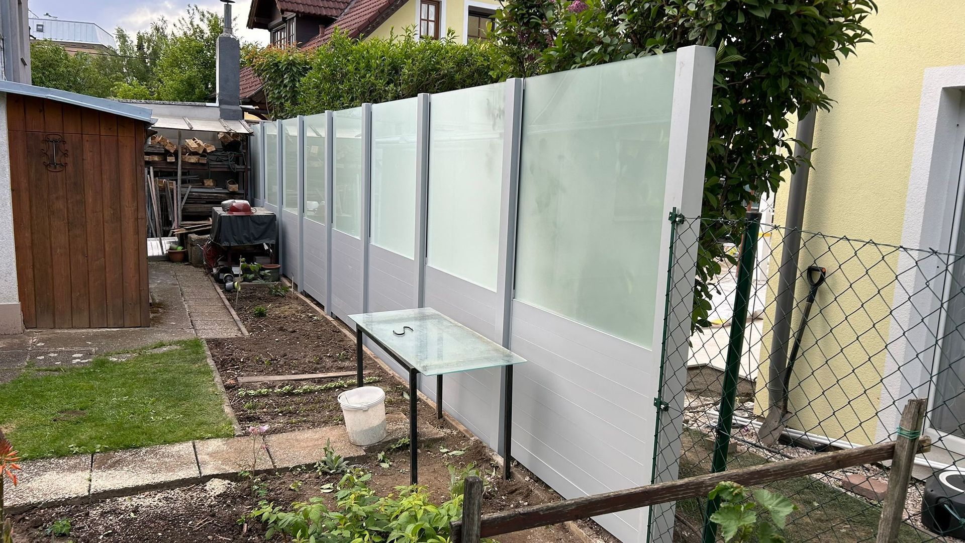 Ein Garten mit Zaun und einem Tisch vor einem Haus.