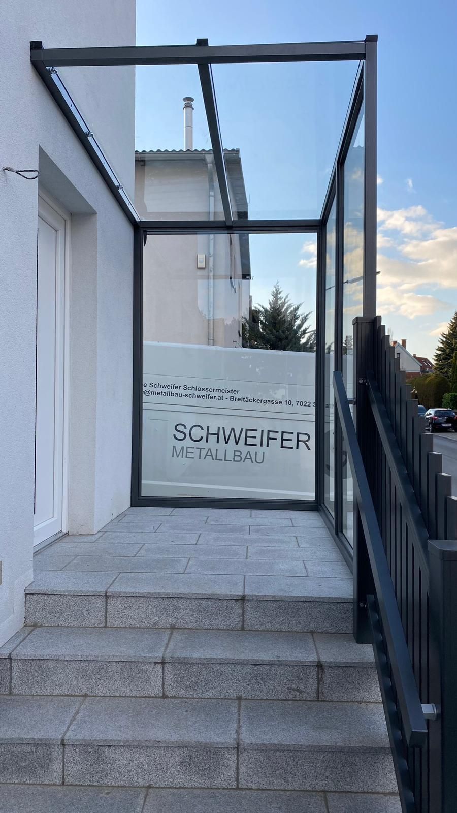 Ein weißes Gebäude mit einer Treppe nach oben und einer Glastür.