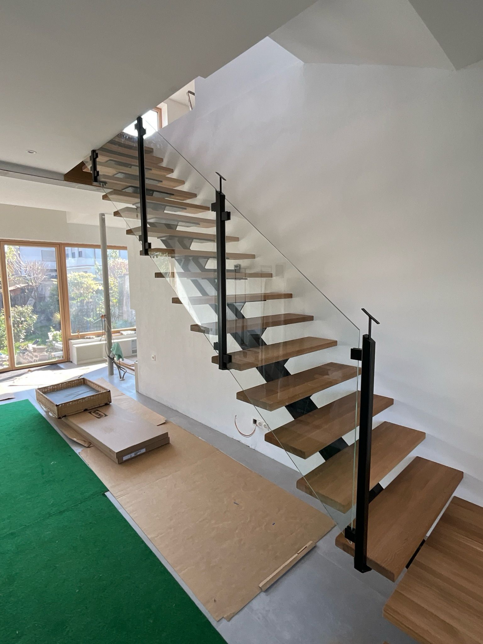 Moderne Treppe mit Holzstufen, schwarzen Metallstützen in einem Innenraum.