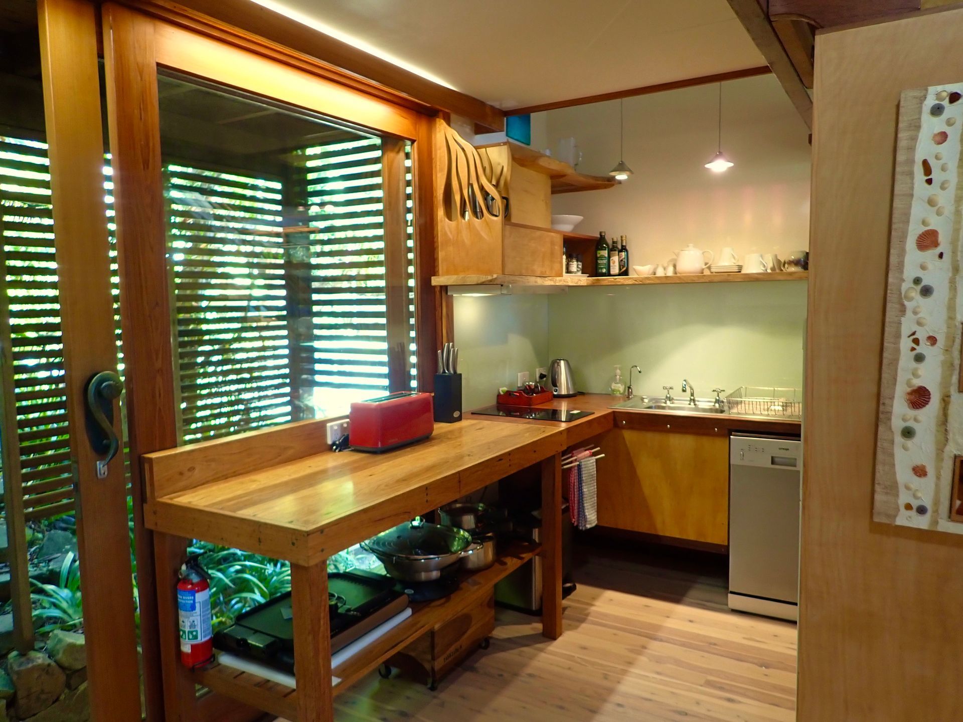 Cozy kitchen with wooden counter, sink, cabinets, and sunlight through slatted window blinds