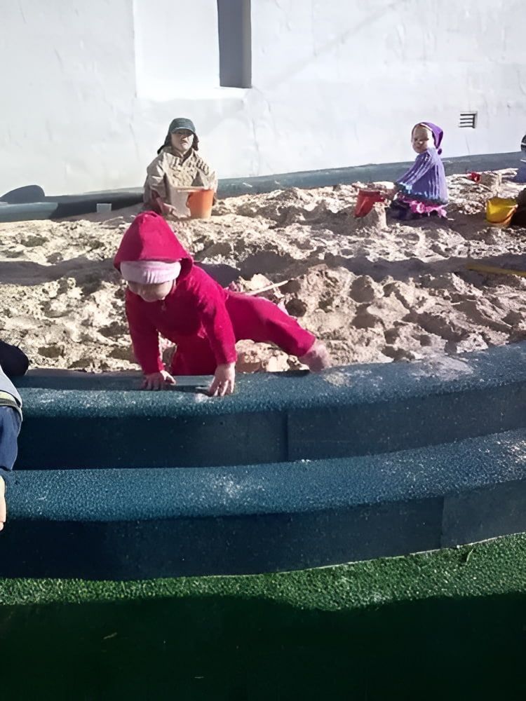A Little Girl in a Red Outfit is Crawling in the Sand — Mt Ousley Pre School in Fairy Meadow, NSW