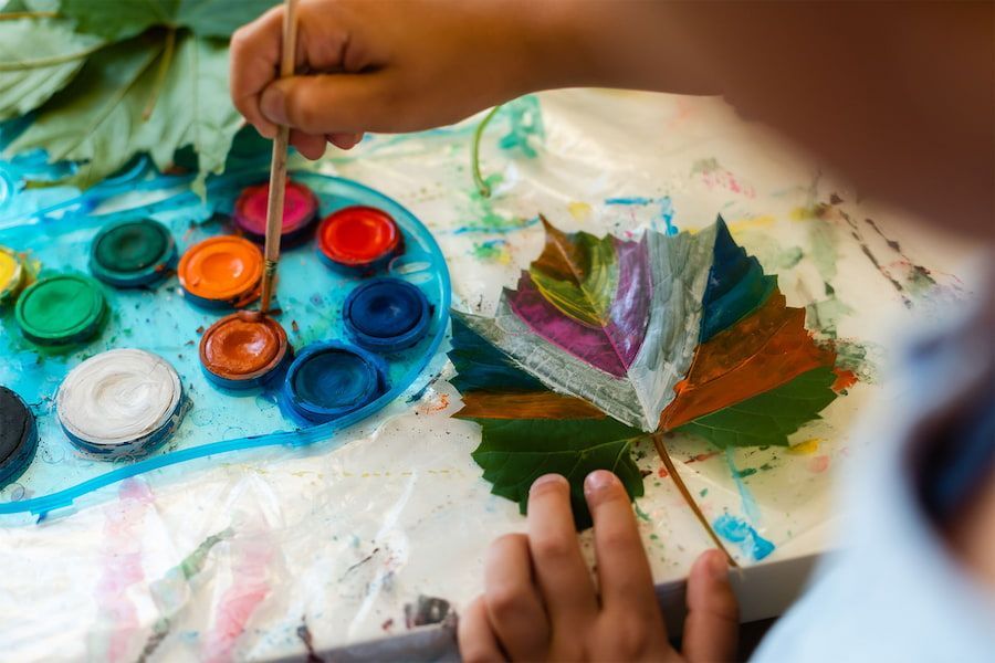 A Child is Painting a Leaf With Water Colours — Mt Ousley Pre School in Fairy Meadow, NSW