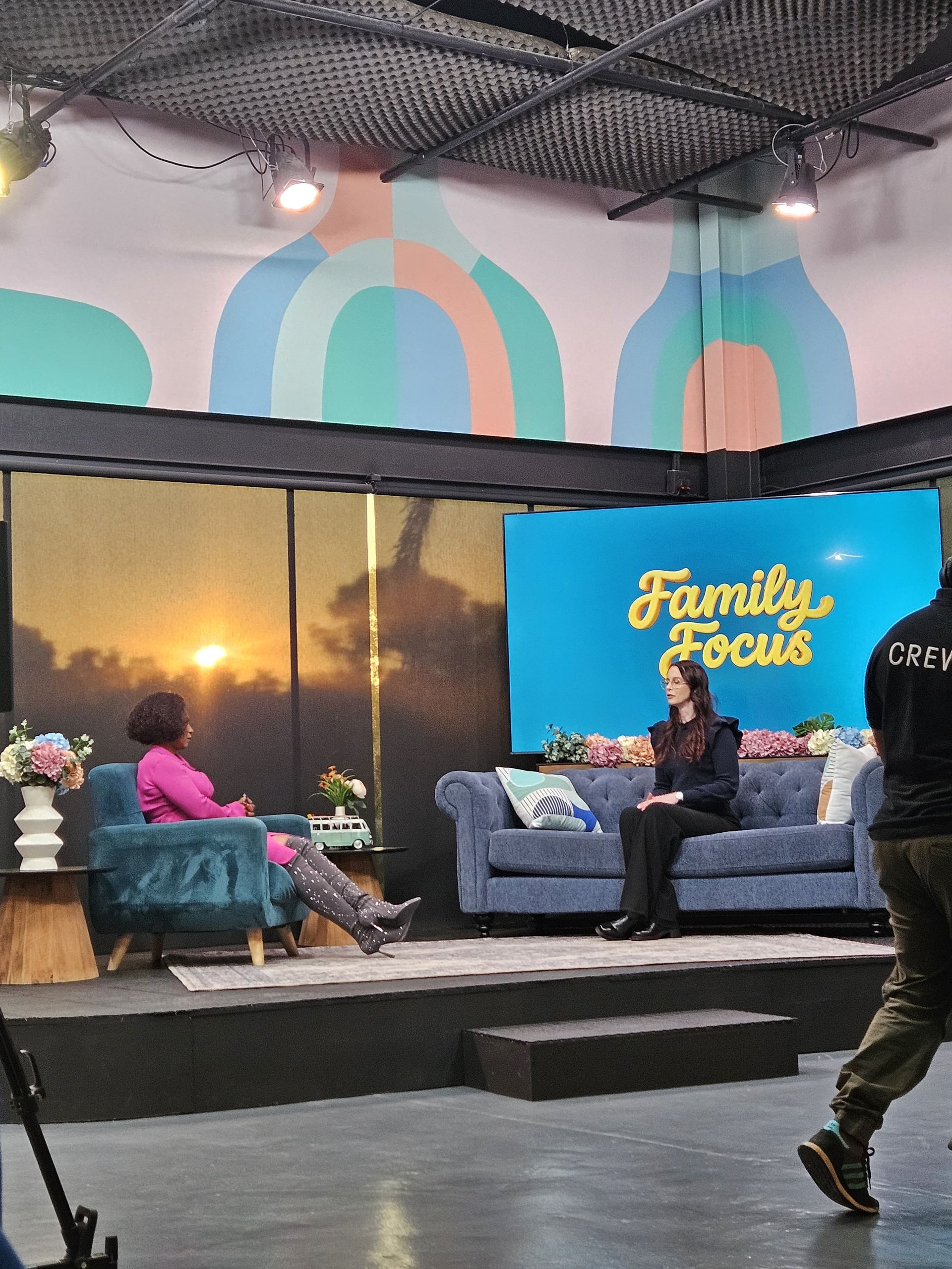 Nikki Russell and Penny Lebyane in a discussion on the SABC2 Eintlek Let's Connect set and a “Family Focus” sign backdrop