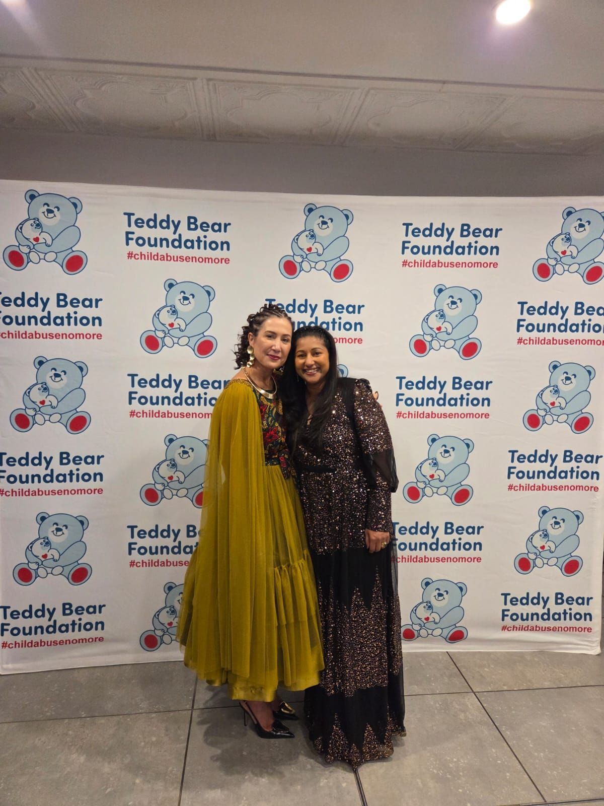 Tricia Moodley and Tanya  Robinson smile while standing at Teddy Bear Foundation Charity Dinner.