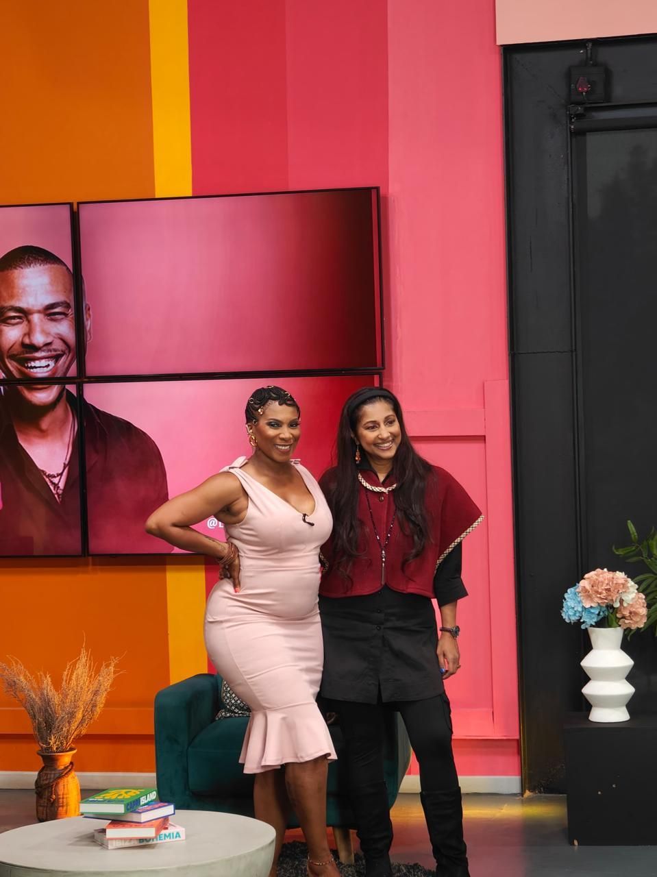 Tricia Moodley and Penny Lebyane smile while standing together in studio set.
