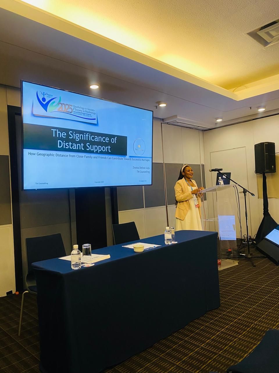Zinzisa Deliwe-Juju  stands at a podium at the PsySAA Congress conference.