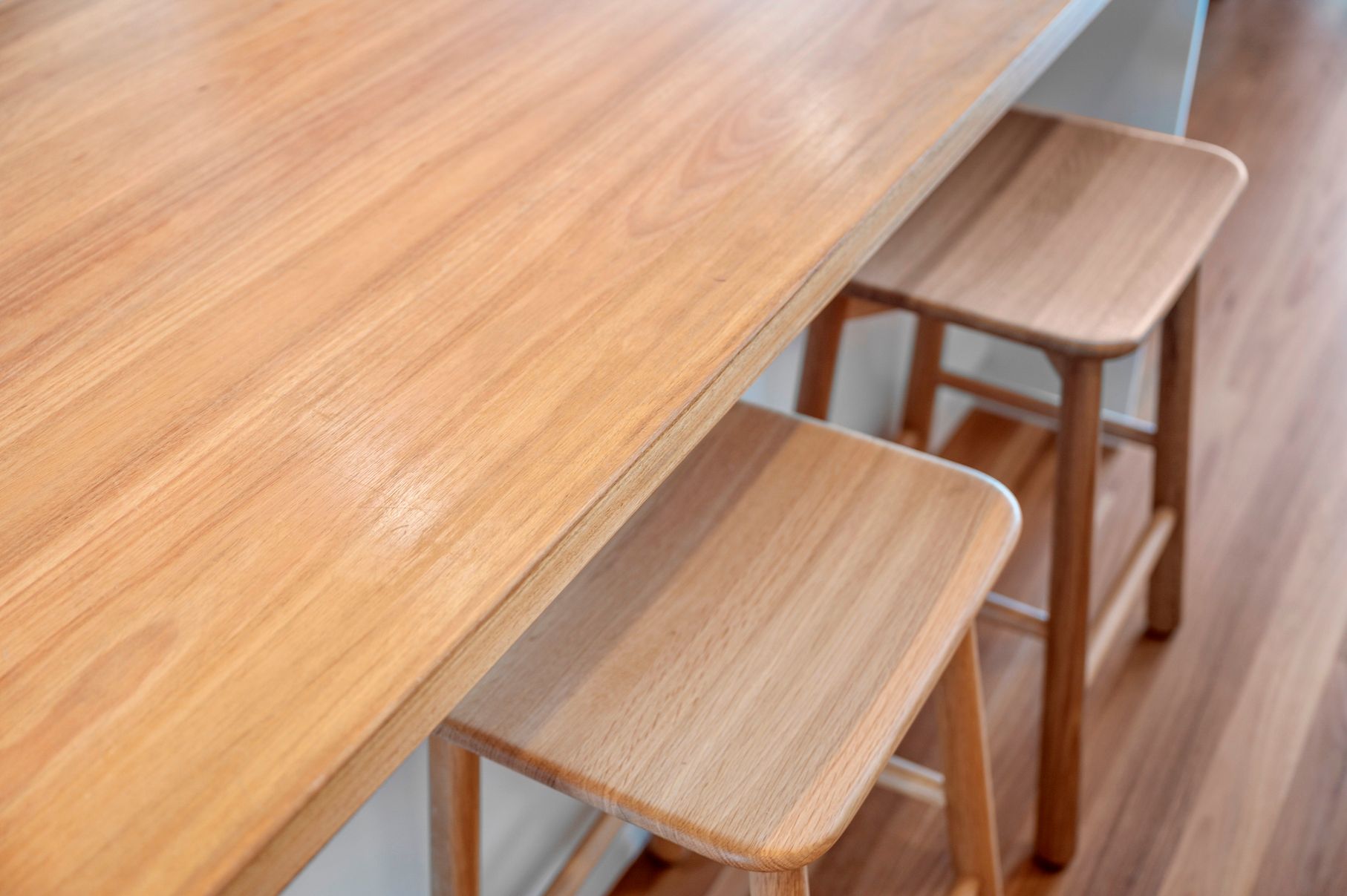 A Kitchen With A Large Island And Two Bar Stools — Plumbe Joinery in Coffs Harbour, NSW