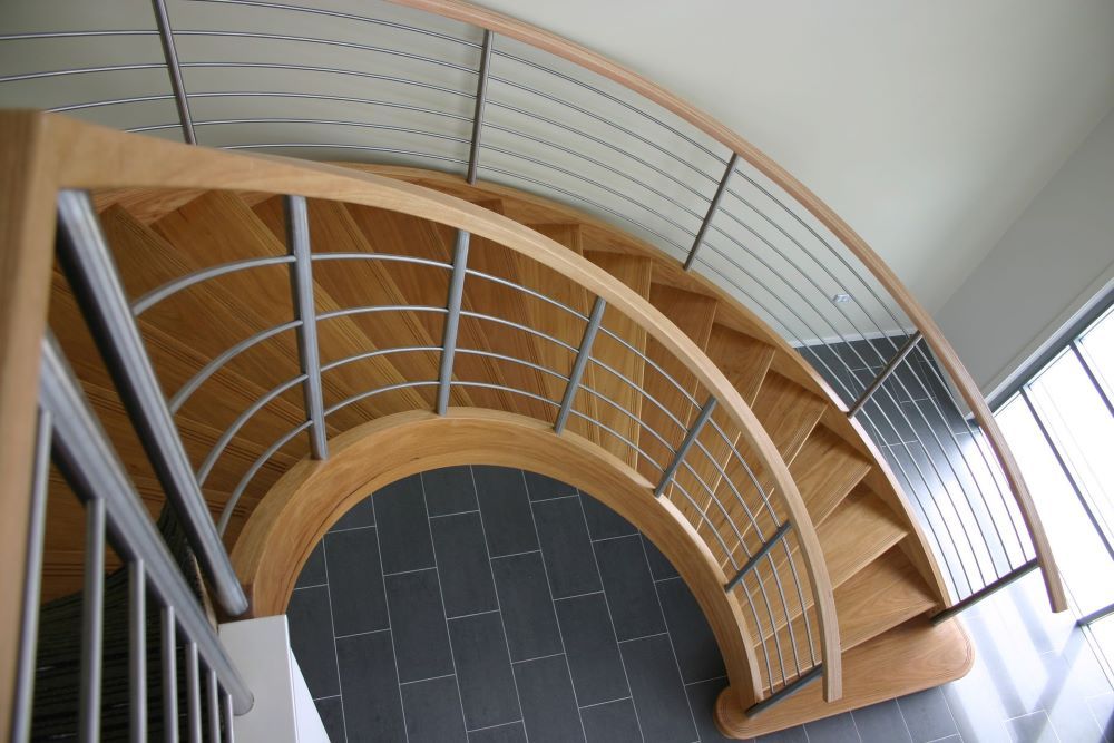 An Aerial View of a Curved Staircase With a Metal Railing — Plumbe Joinery in Coffs Harbour, NSW