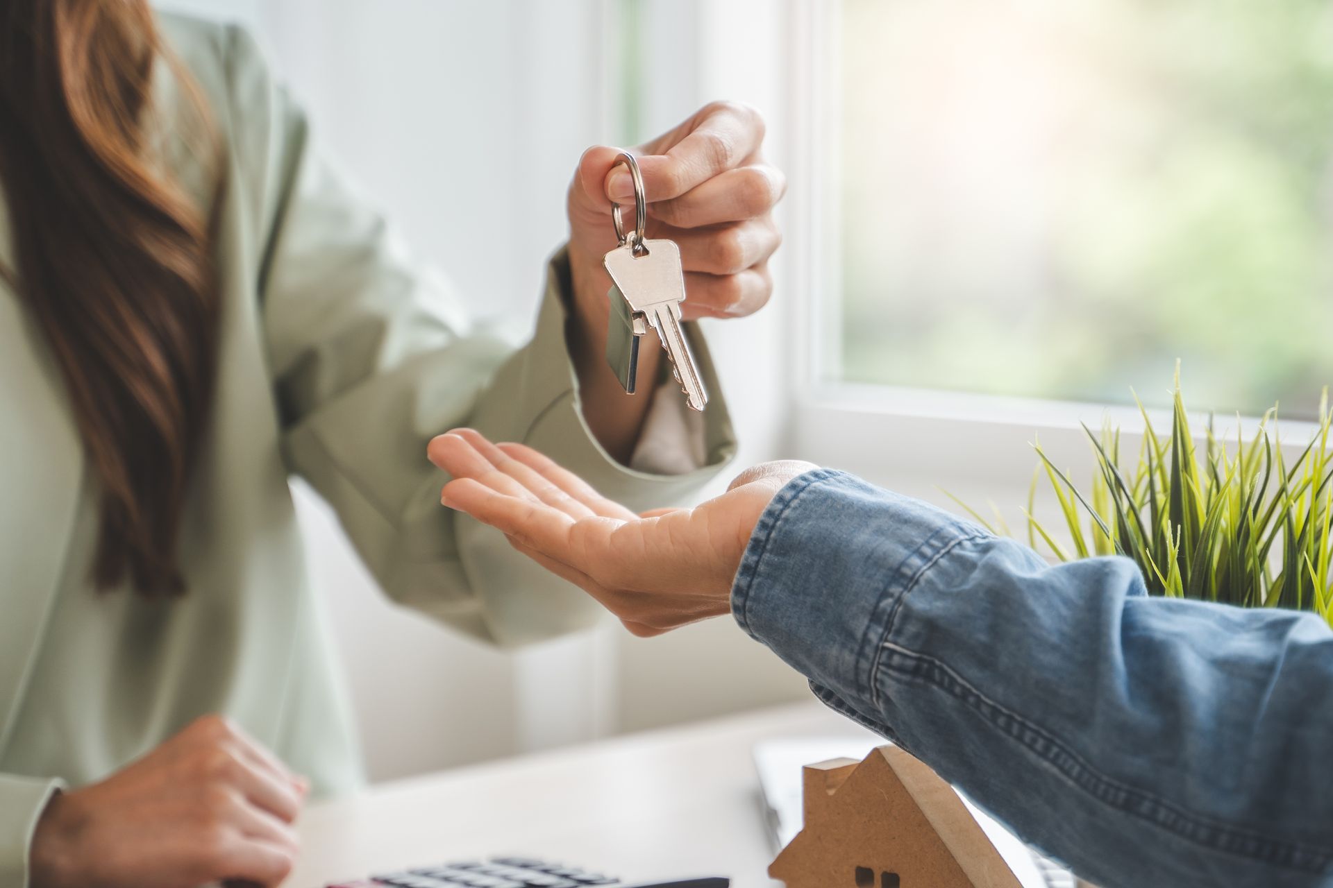 Handing over house keys at a desk, with a small house model nearby