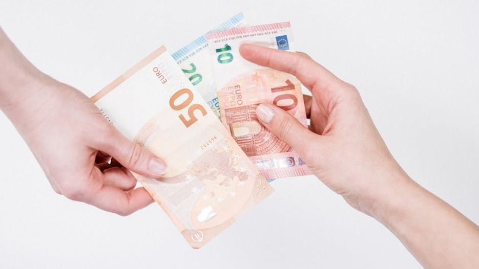 A person is handing another person a bunch of money.