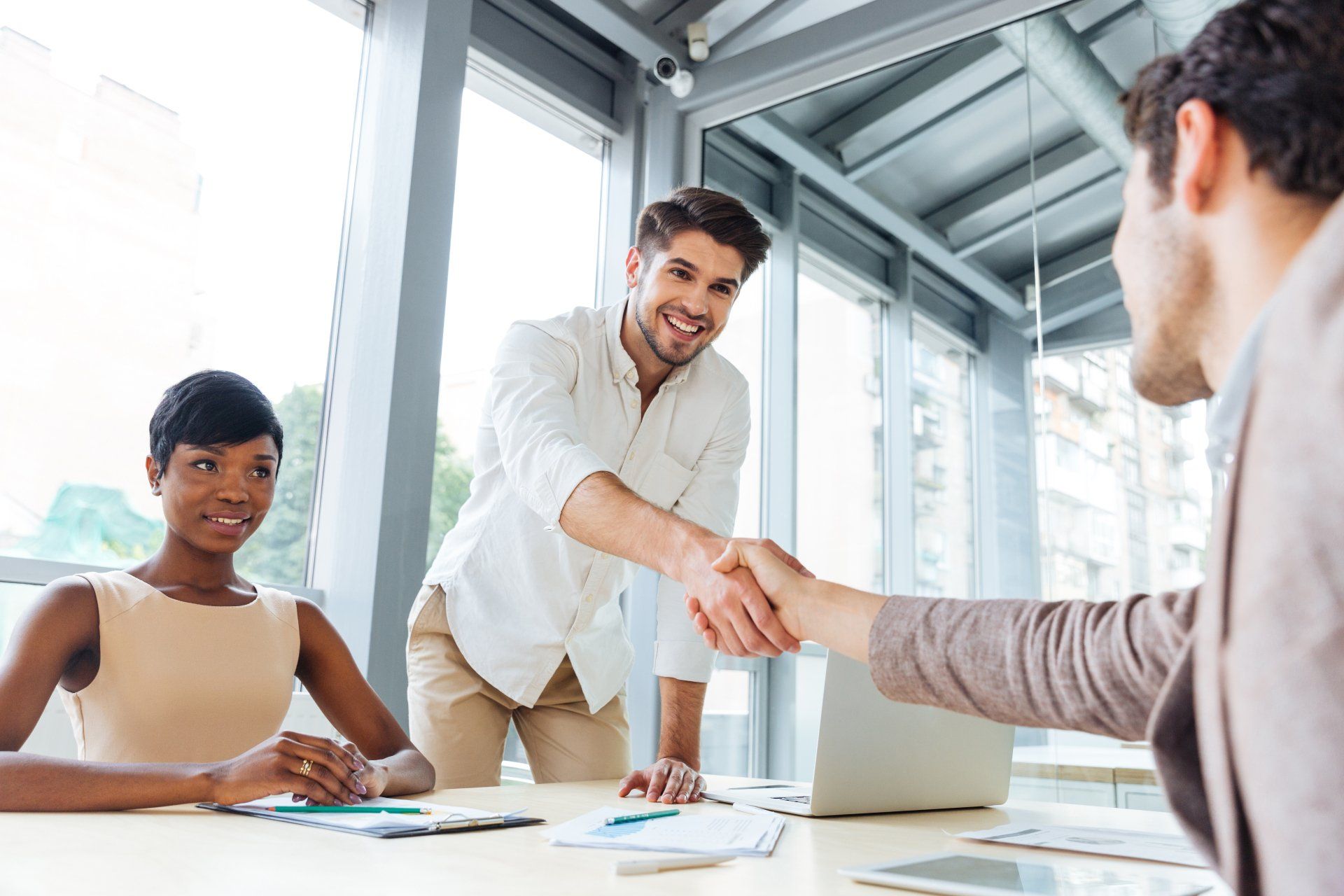 group business meeting ending with two businessmen shaking hands in an office