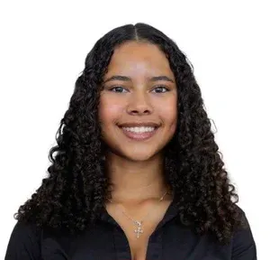 Smiling person with curly dark hair wearing a black top against a white background