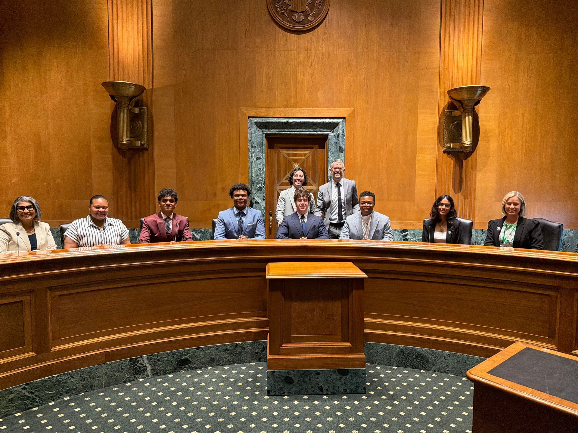 People seated behind a curved wooden dais in a formal council chamber