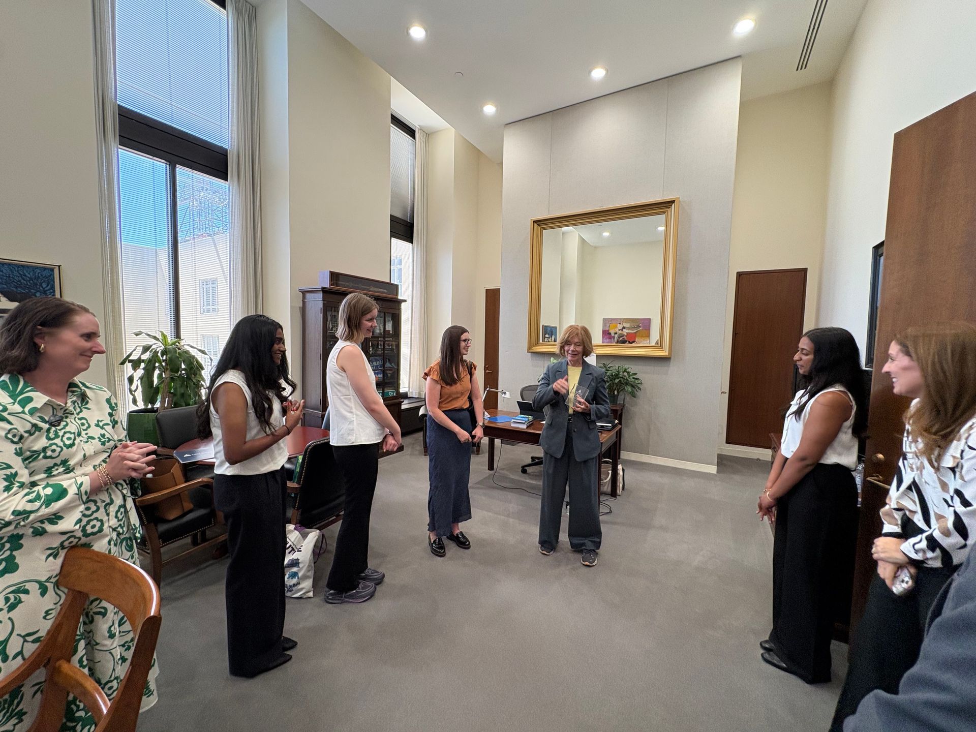 People standing in a bright museum gallery during a guided tour, near a large framed painting.