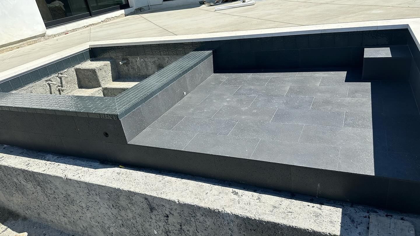 Concrete rooftop pool or water feature with raised ledges and a dark rectangular basin area