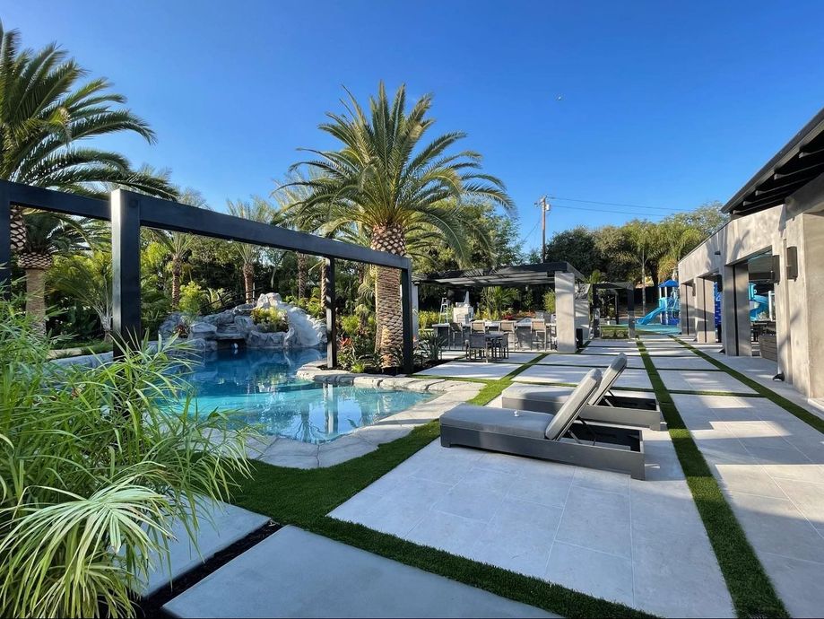 Modern resort pool with cabana loungers, palm trees, and a sunny blue sky