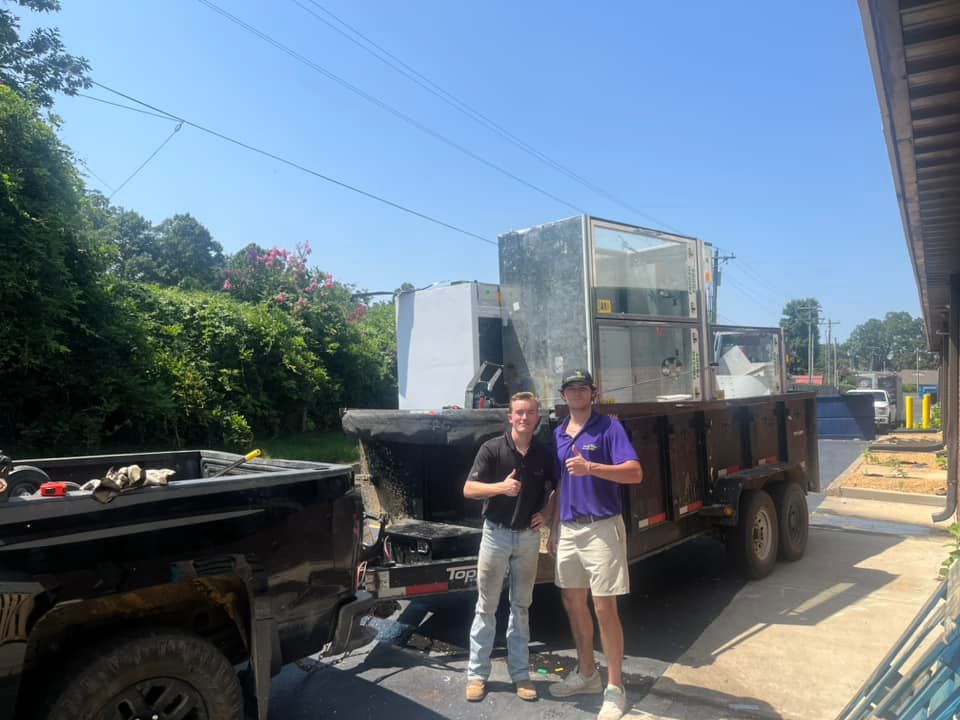 Two men beside a truck hauling HVAC units on a sunny day. They are giving a thumbs up.
