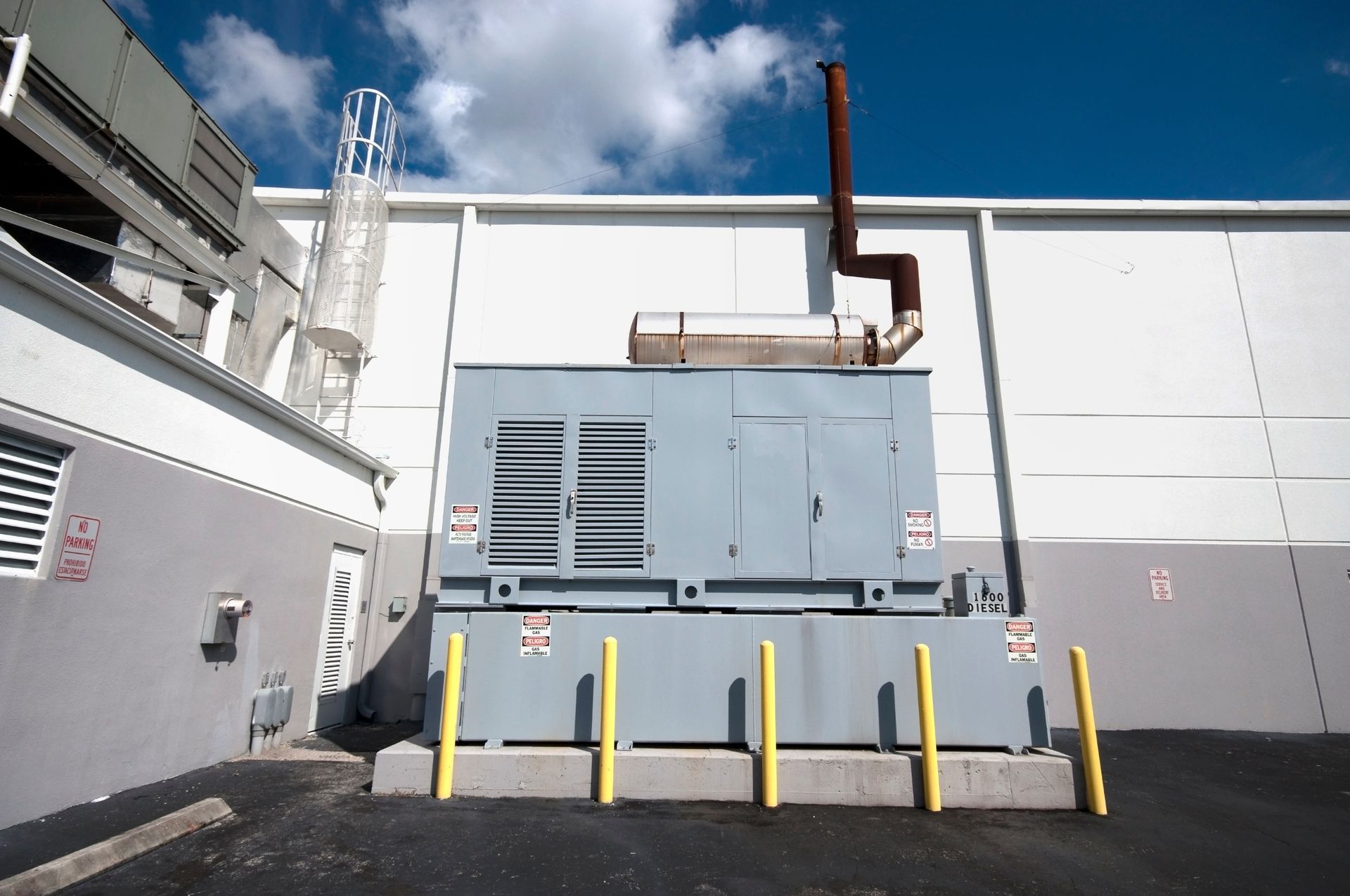 Un b&acirc;timent en brique rouge avec trois bornes de recharge pour v&eacute;hicules &eacute;lectriques fix&eacute;es au mur et un toit noir avec panne