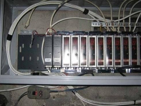 Un pannello di controllo elettrico che ospita diversi moduli display a LED verticali e il relativo cablaggio all'interno di un armadio metallico grigio.