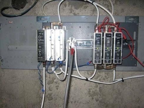 Un quadro elettrico industriale con molteplici componenti modulari, cablaggio e montaggio su guida DIN metallica su base grigia.