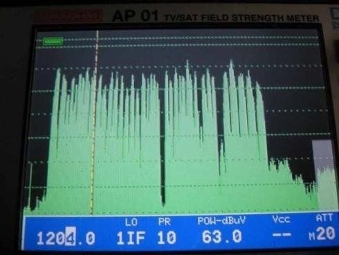 Lo schermo di un analizzatore di spettro visualizza una forma d'onda verde delle frequenze del segnale satellitare con un livello di potenza di 63,0 dBµV.