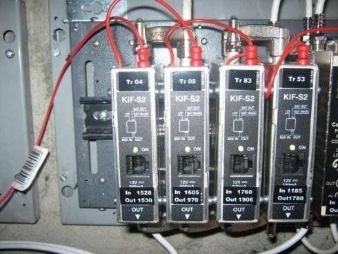 Quattro trasmettitori di segnale KIF-S2 montati su un supporto metallico, collegati tramite cavi coassiali rossi e bianchi.