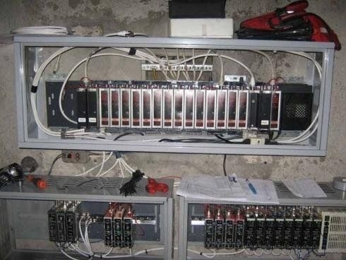 Pannelli di controllo industriali con display digitali e cablaggio elettrico montati su un muro di pietra grezza.