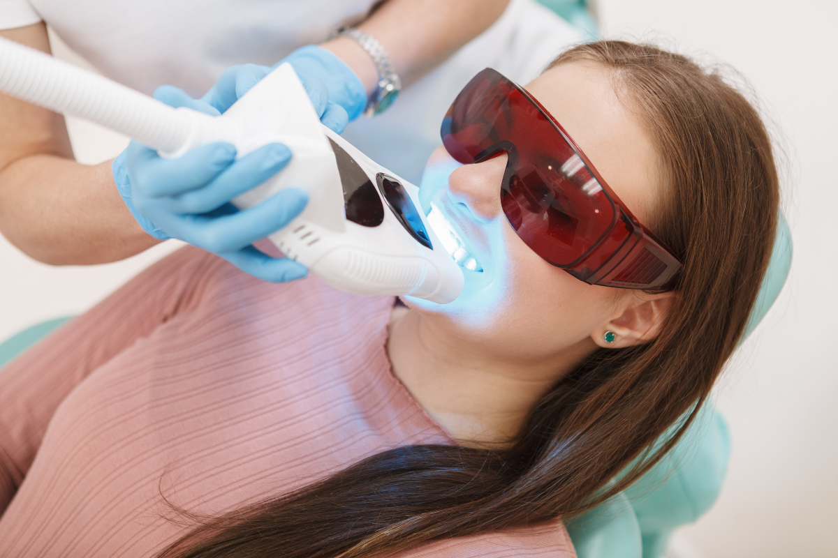 Dentist using a blue light on a patient wearing red protective glasses during a dental treatment