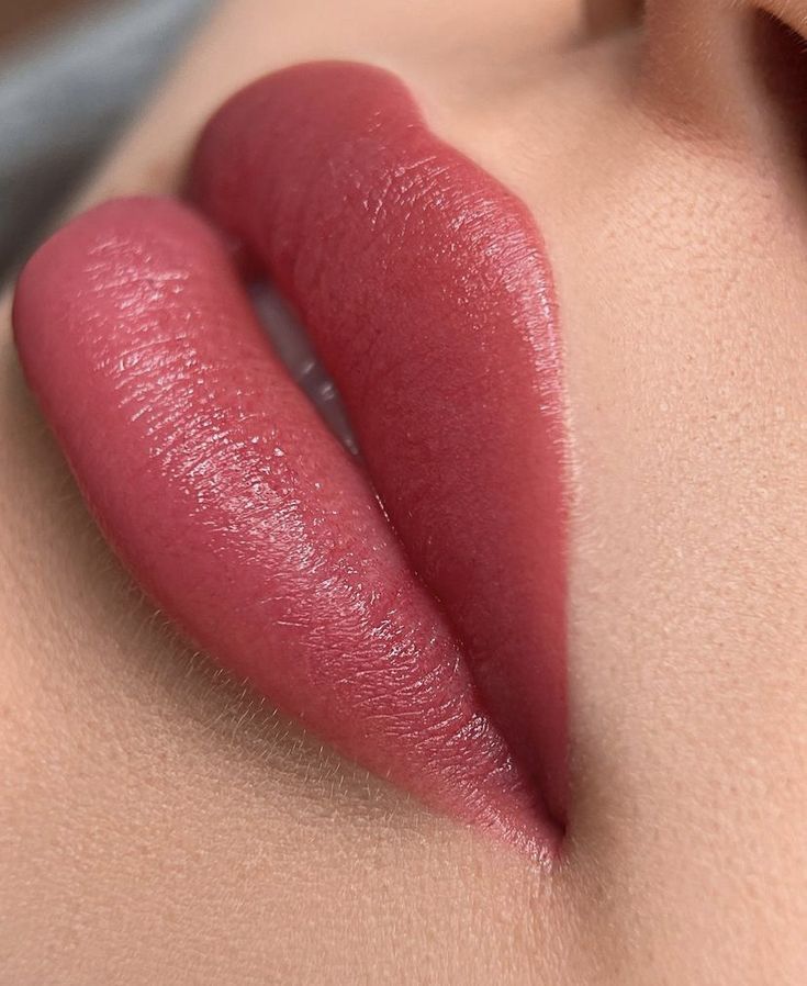 Close-up of plump, pink lips, likely after a cosmetic procedure, against light skin.