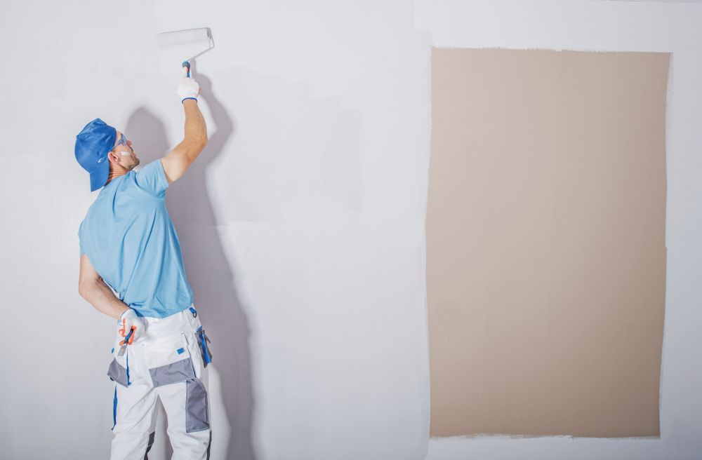 Painter in Blue Uniform Using a Paint Roller on a White Wall — Jamie Frankham Painting in Casino, NSW
