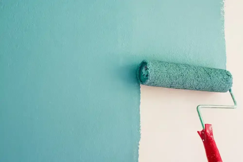 Paint Roller Applying Teal Paint to a White Wall — Jamie Frankham Painting in Goonellabah, NSW