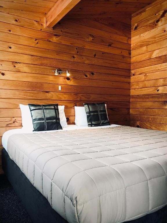 A hotel room with a bed , chair , table and nightstand.