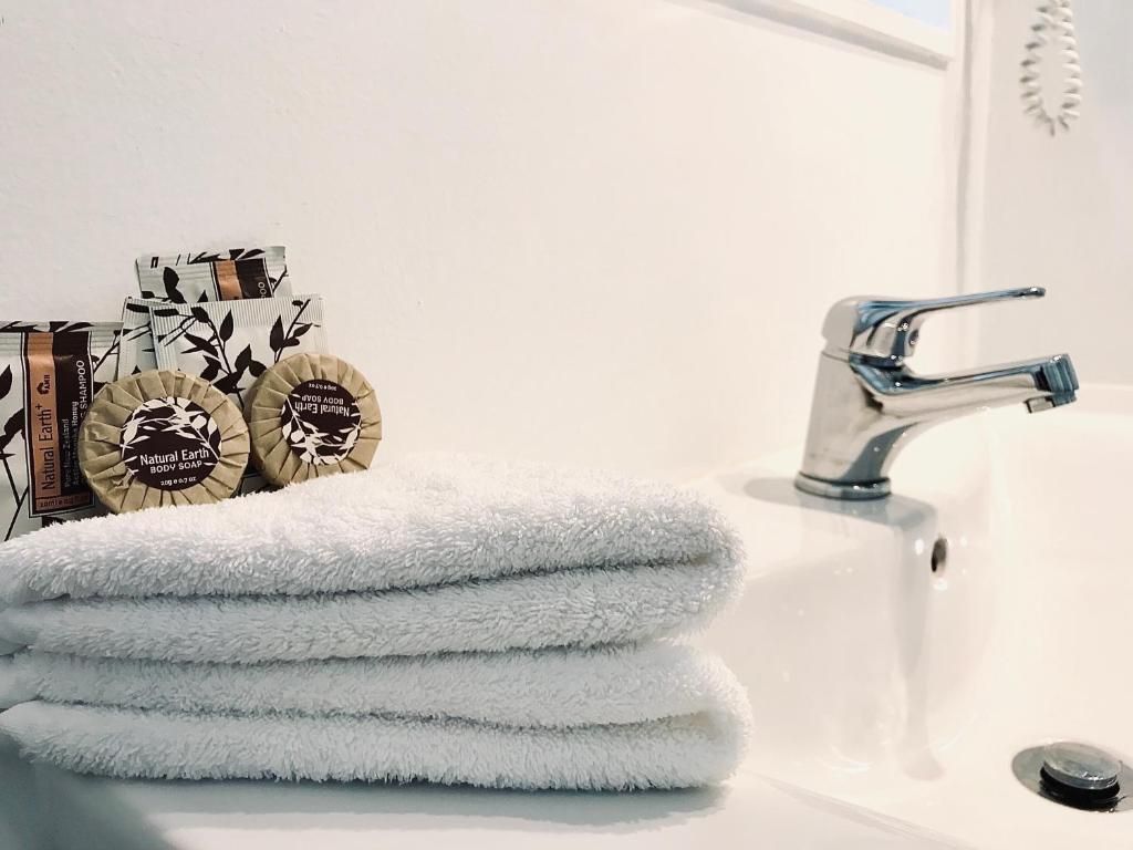 A bathroom sink with a stack of towels and soap on it.