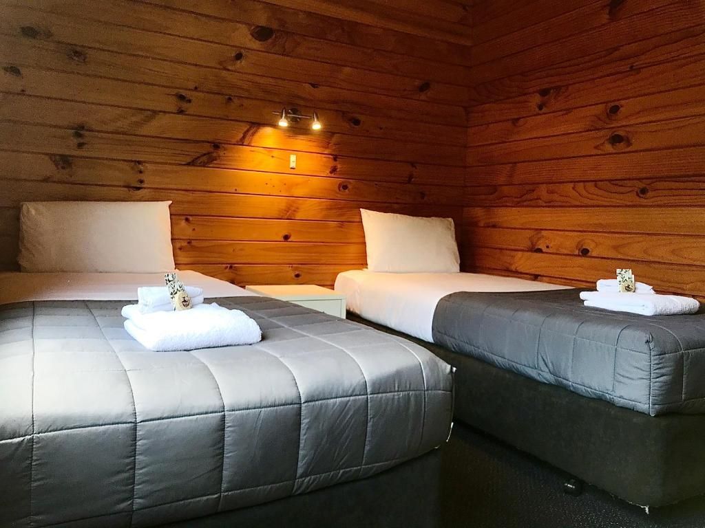 A bedroom with two beds and a wooden wall