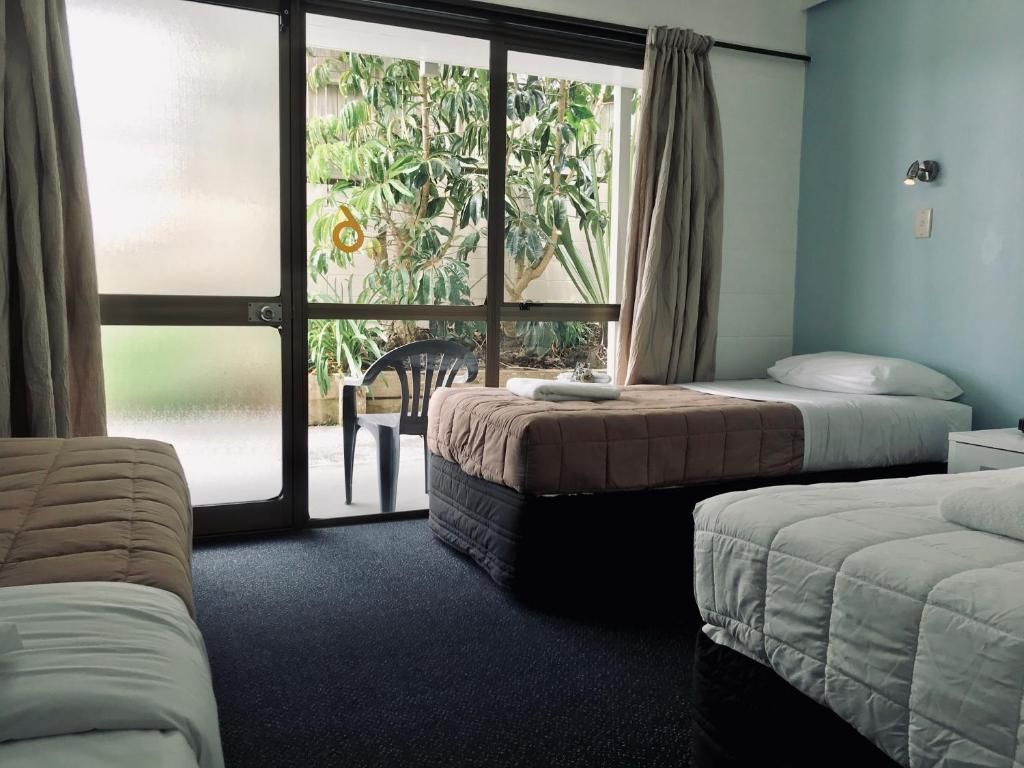 A hotel room with three beds and a sliding glass door