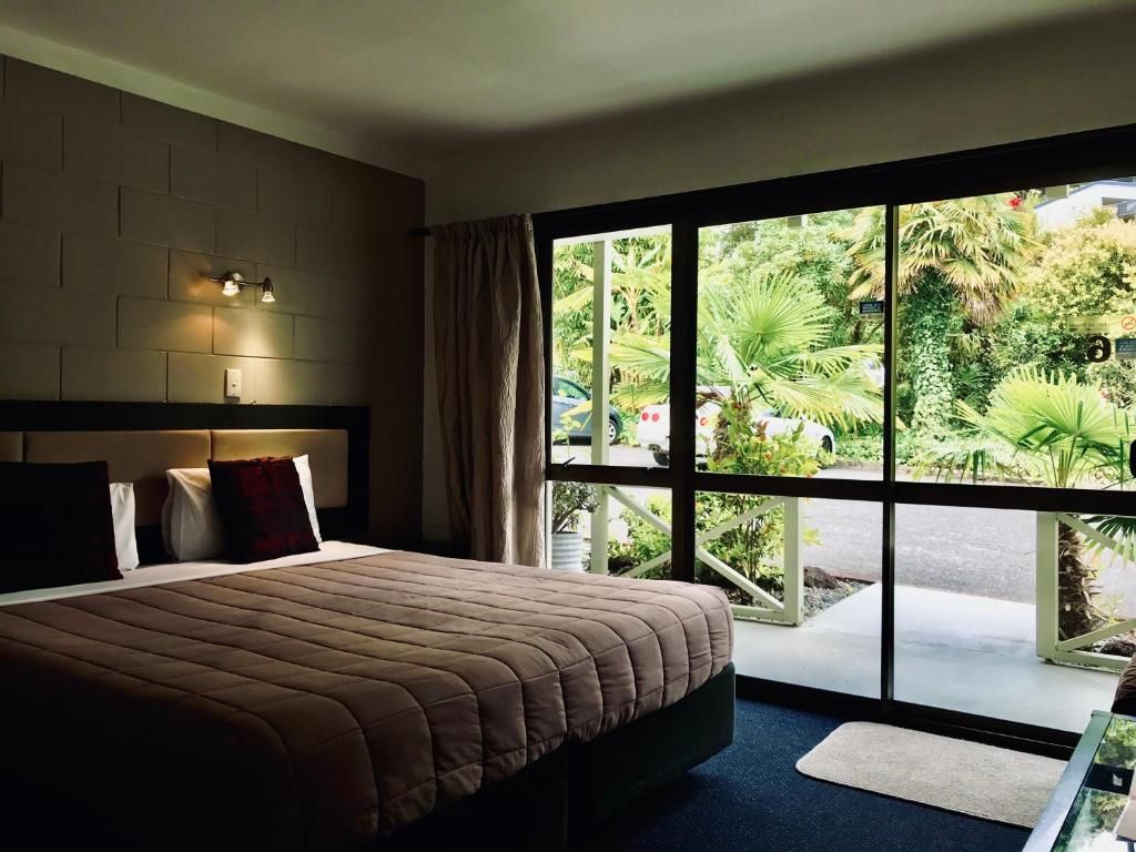 A hotel room with a bed , chair , table and nightstand.