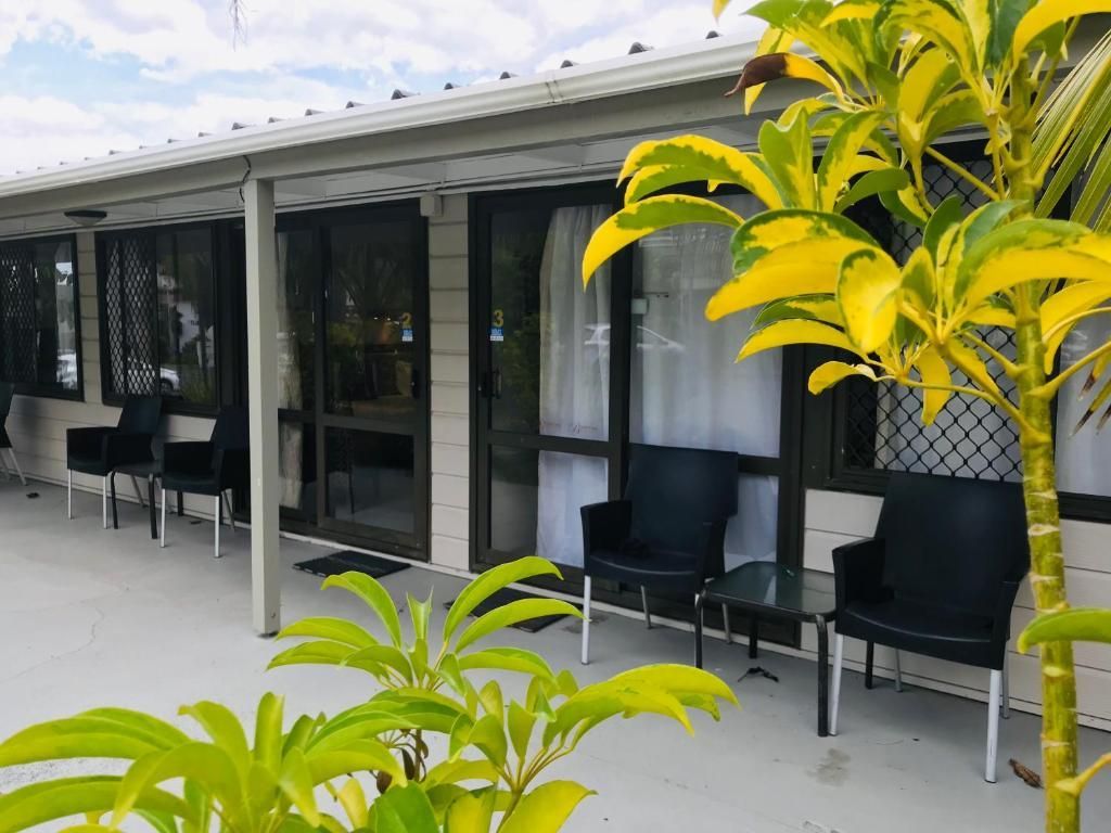A patio with chairs , tables and a tree in front of a house.