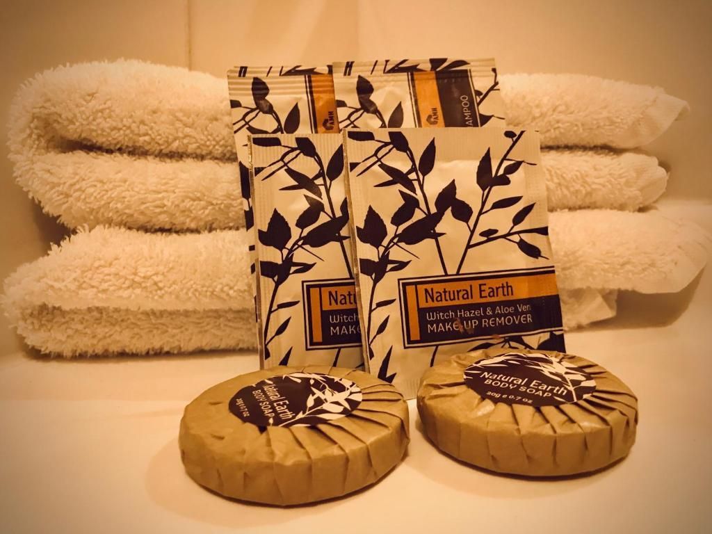 A stack of towels sits next to two soaps and two bottles of natural earth