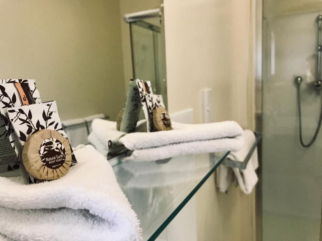 A bathroom with towels and soap on a glass shelf.
