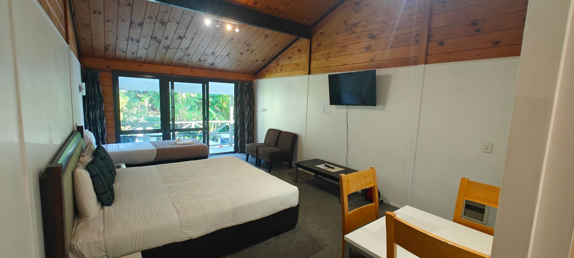 A hotel room with two beds , a table and a television.