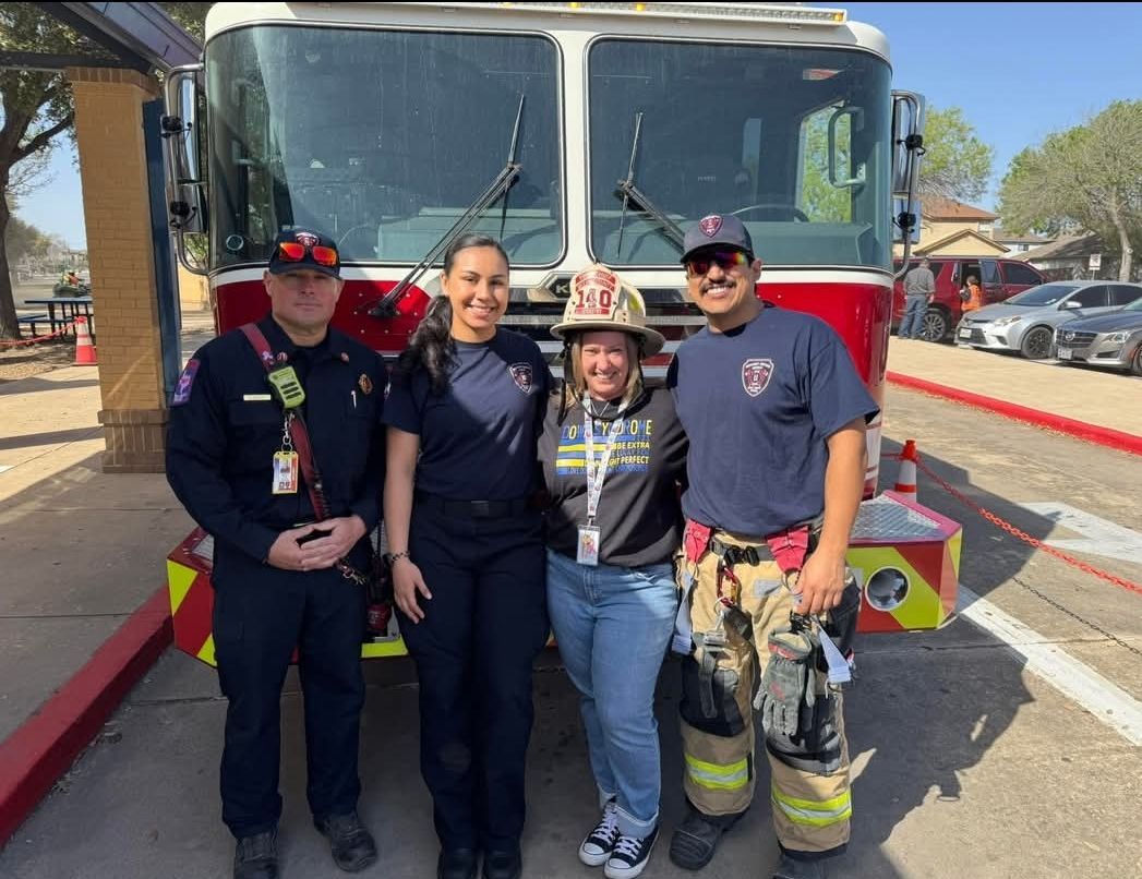 A group of children are standing around a fireman wearing a helmet.