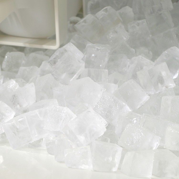 A close-up of a pile of clear, cubed ice pieces spilling out from a white container.