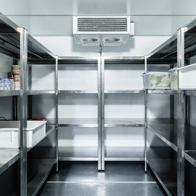 A symmetrical view of a commercial walk-in refrigerator with stainless steel shelving and a ceiling cooling unit.