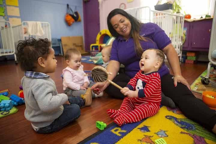 a woman is sitting on the floor playing with three babies .