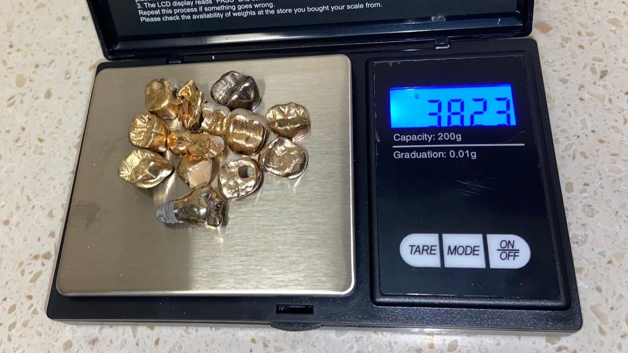 Gold dental crowns on a digital scale, reading 38.23 grams.