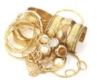 Gold jewelry: bracelets, rings, and necklaces, piled together, some with intricate patterns and pearls.