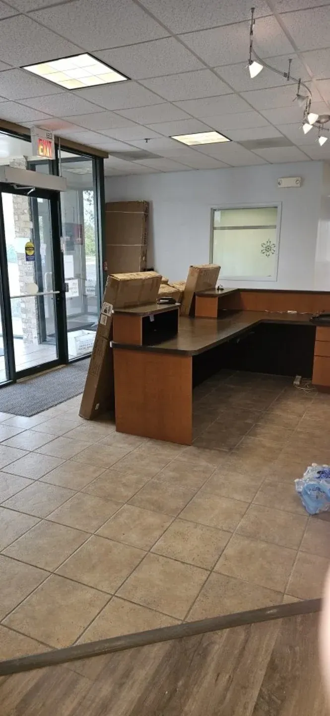 Empty office lobby with a reception desk, glass entrance, and tiled floor
